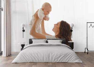 Happy smiling mother with baby having fun together on white of the curtains of the window background Wall mural