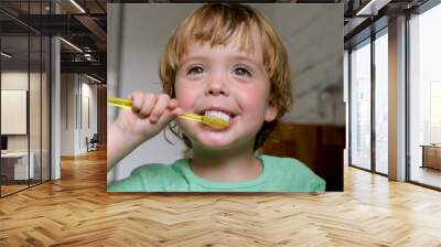 Little blond boy learning brushing his teeth in domestic bath. Kid learning how to stay healthy. Health care concept Wall mural