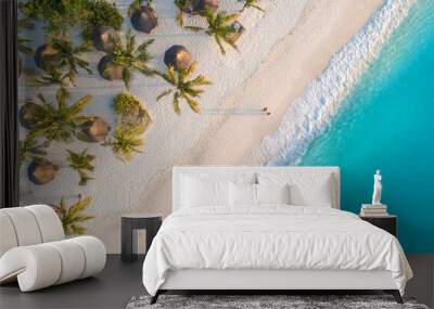 Aerial view of umbrellas, palms on the sandy beach of Indian Ocean at sunset. Summer holiday in Zanzibar, Africa. Tropical landscape with palm trees, parasols, white sand, blue water, waves. Top view Wall mural