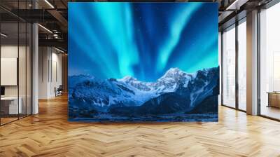 Aurora borealis above the snow covered mountain range in europe. Northern lights in winter. Night landscape with green polar lights and snowy mountains. Starry sky with aurora over the rocks. Space Wall mural