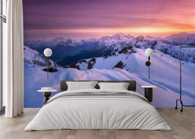 Colorful red sky with clouds and bright sunlight over the snow covered mountains at sunset in winter. Beautiful wintry landscape with snowy rocks and hills at dusk. Scenery with alps at frosty evening Wall mural