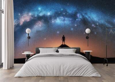 Glowing Milky Way and man on mountain peak at starry night. Silhouette of a guy on the hill, sky with bright stars. Galaxy. Space landscape with milky way arch. Panoramic nightscape. Travel. Concept Wall mural