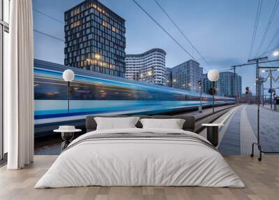 High speed train in motion on the railway station at dusk. Moving blue modern intercity passenger train, railway platform, buildings, city lights. Railroad in Vienna, Austria. Railway transportation Wall mural