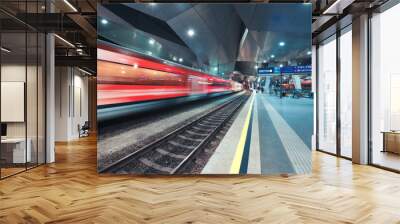 High speed train in motion on the railway station at night. Moving red modern intercity passenger train, railway platform, architecture, city lights. Modern train station in Vienna, Austria. Railroad Wall mural