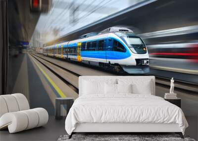 High speed train in motion on the train station at sunset. Blue modern intercity passenger train with motion blur effect. Railway platform. Railroad in Europe. Commercial transportation. Concept Wall mural