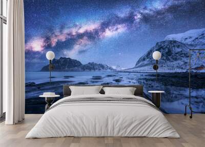 Milky Way above snow covered mountains and rocky beach in winter at night in Lofoten Islands, Norway. Cosmic landscape with starry sky, water, stones, snowy rocks, bright milky way. Beautiful space Wall mural