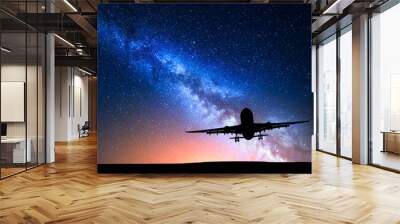 Milky Way and silhouette of a airplane. Landscape with passenger airplane is flying in the starry sky at night. Space background. Commercial airliner on the background of colorful Milky Way. Aircraft Wall mural