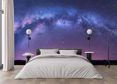 Milky Way arch. Fantastic night landscape with bright arched milky way, purple sky with stars, pink light and hills. Beautiful scene with universe. Space background with starry sky. Galaxy and nature Wall mural