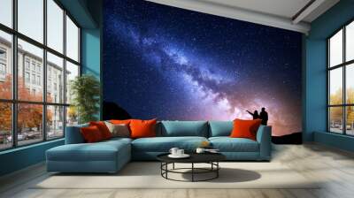 Milky Way with people on the mountain. Landscape with night sky with stars and silhouette of standing happy man and woman who pointing finger in starry sky. Milky way with travelers. Beautiful galaxy Wall mural