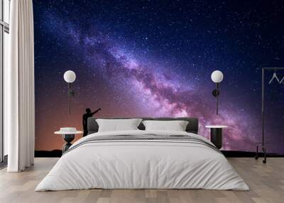 Milky Way with silhouette of a standing man pointing finger in night starry sky on the hill. Colorful night landscape. Beautiful Universe, travel background with purple sky yellow light. Space Wall mural