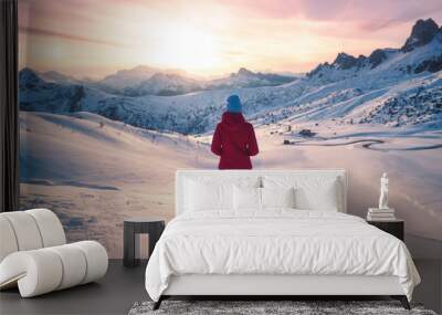 Young woman in snowy mountains at sunset in winter. Landscape with beautiful slim girl on the hill against snow covered rocks and colorful sky with clouds in the evening. Travel in Dolomites. Tourism. Wall mural