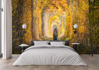 Young woman walking on the railroad in Tunnel of Love in Ukraine in autumn at sunset. Girl with backpack on railway station in tunnel of colorful trees in fall. Railroad in beautiful forest. Lifestyle Wall mural