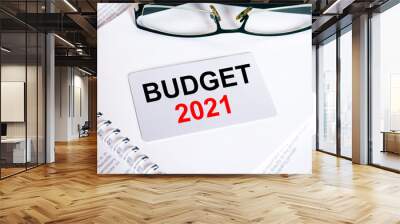 Text Budget 2021 on a business card lying on a notepad with eyeglasses and text documents Wall mural