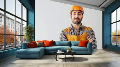 A handsome young male construction worker stands with his arms crossed against the white background, wearing an orange helmet and yellow overalls, looking at the camera копия Wall mural