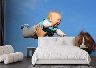 father throws up his son in sky, having fun Wall mural