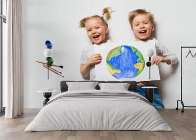 Ecology concept with two prety little kids painting earth on white background Wall mural