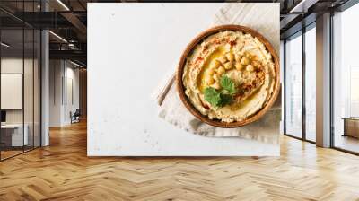 Hummus dip with chickpea, and parsley in wooden plate on white background Wall mural