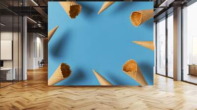 Ice cream cones levitate frame over blue background Wall mural