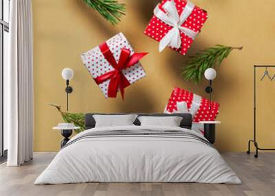 Polka dot pattern red gift box with ribbon and green tree branch falling on gold, brown background Wall mural