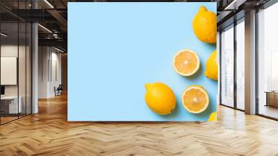 Ripe lemons flat lay with leaves on blue background Wall mural