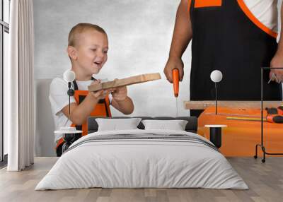 Dad and son working together in the workshop,sawing wooden planks. Wall mural