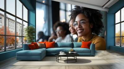 Diverse black woman student with glasses, classmates in background sitting in university class during lecture. Wall mural