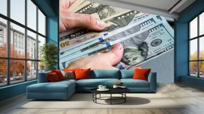 Hand holding one hundred and fifty dollar banknotes, laptop keyboard in background. Wall mural