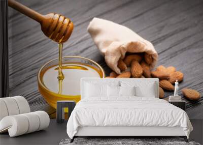 Honey in a bowl, dipper and almond nuts on a wooden background. Wall mural