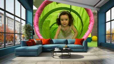 little girl crawls inside toy tunnel at childrens holiday Wall mural