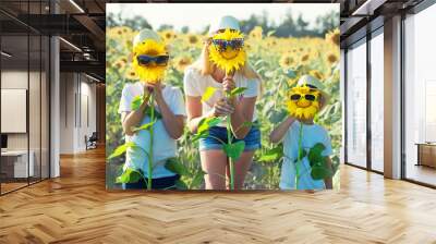 Mom and sons are walking around the field with sunflowers. A happy day.	 Wall mural