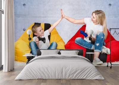 Mother and son sit on chairs bags and play video games .Emotions.	 Wall mural