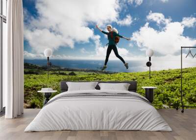 Portrait of fit positive girl jumping in the air on cloudy background with ocean view. Life people energy freedom concept. Sao Miguel island, Azores. Wall mural