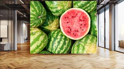 Red ripe watermelon cut in half on a pile of ripe watermelons in the field. A red cut watermelon view from above. Wall mural