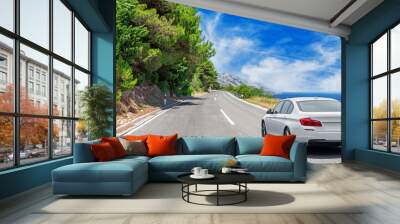 A white car drives along the sea coastline on a sunny summer day. Wall mural