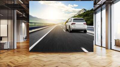 A white car rushing along a high-speed highway in the sun. Wall mural