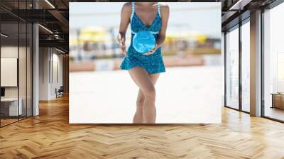 A girl in a blue sports dress with a volleyball ball, running on the sand on the volleyball court Wall mural