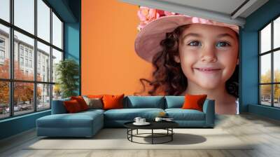 Young smiling child girl with blooming floral hat on orange background Wall mural