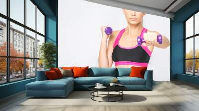 Close-up of concentrated, serious young fitness woman lifting dumbbells smiling and energetic. Isolated over white background. Wall mural