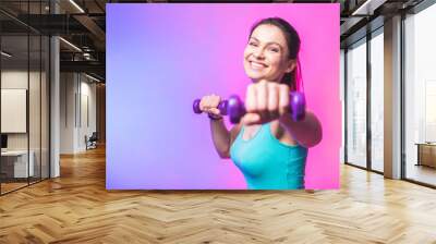 Close-up portrait of young attractive happy woman in sport clothes with beautiful smile holding weight dumbbell doing fitness workout isolated on white background in healthy lifestyle concept Wall mural