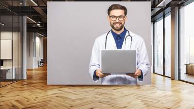 Concentrated male doctor using laptop isolated over grey background. Wall mural