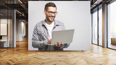 confident business expert. confident young handsome man in shirt holding laptop and smiling while st Wall mural