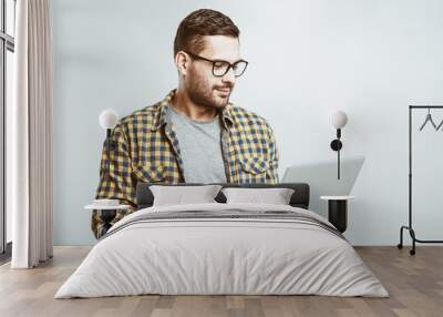 Confident business expert. Confident young handsome man in shirt holding laptop and smiling while standing against white background Wall mural