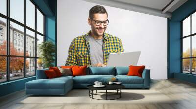 Confident business expert. Confident young handsome man in shirt holding laptop and smiling while standing against white background Wall mural