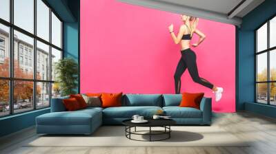 Full length picture of a sports woman running in studio over pink background. Wall mural