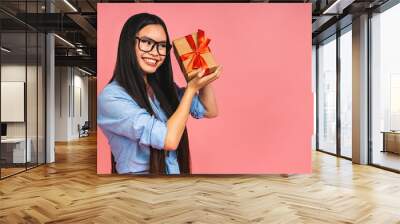 Happy beautiful asian woman holding gift box isolated on pink background. Teenage girls in love, Receiving gifts from lovers. New Year, Christmas and Valentines Day concept Wall mural