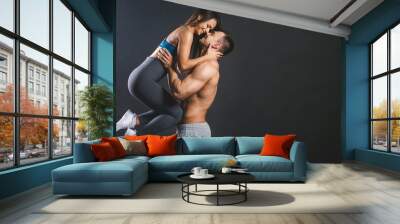 Happy smiling sporty young sexy couple isolated over black background. Wall mural