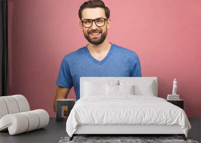 Happy young man in casual standing and using tablet over pink background Wall mural