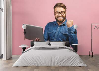 I'm a winner! Happy man holding laptop and celebrating his success over pink background. Wall mural