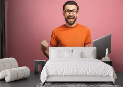 Image of happy excited young man posing isolated over pink background wall using laptop computer make winner gesture. Wall mural