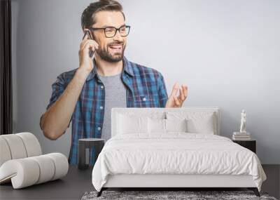 Oh, great news! Smiling young casual man talking on the phone on the grey background. Isolated. Wall mural